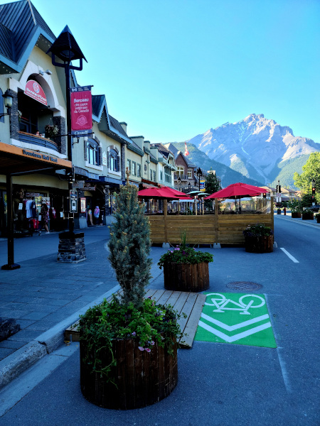 Imagen típica del pueblo de Banff, con sus restaurantes con terrazas y las Montañas Rocosas al fondo