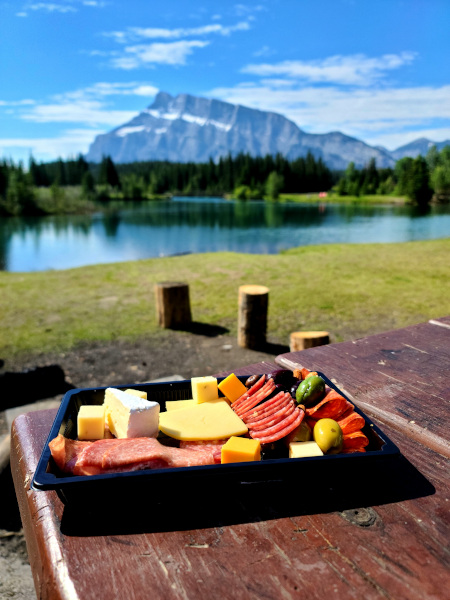 Disfrutando de una charcutería de IGA en Cascade Ponds Picnic Area con las Montañas Rocosas al fondo